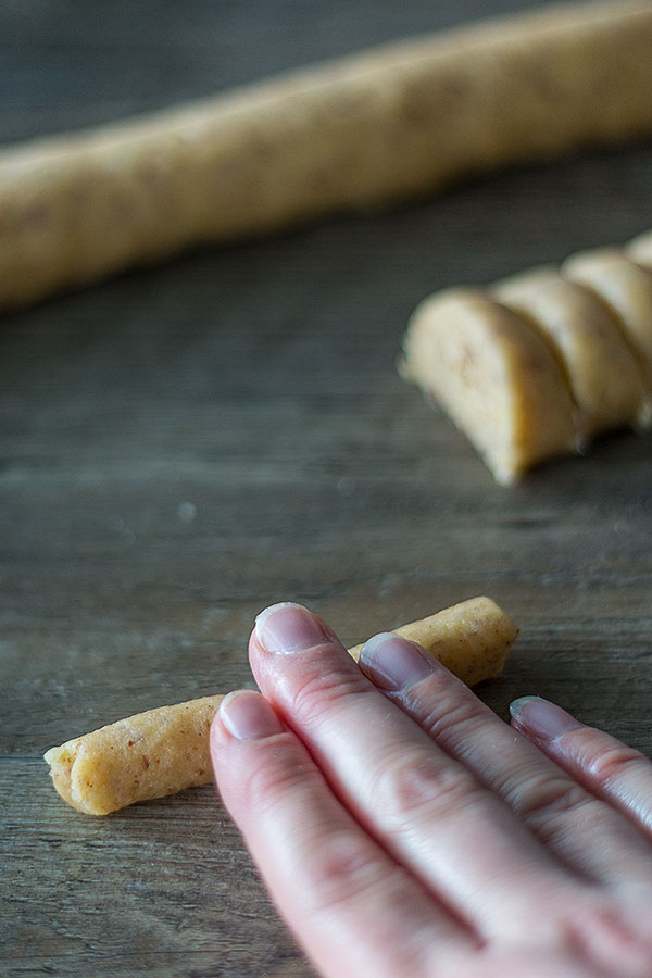 Kleine Teigstücke für Vanillekipferl mit den Händen zu kleinen Rollen formen