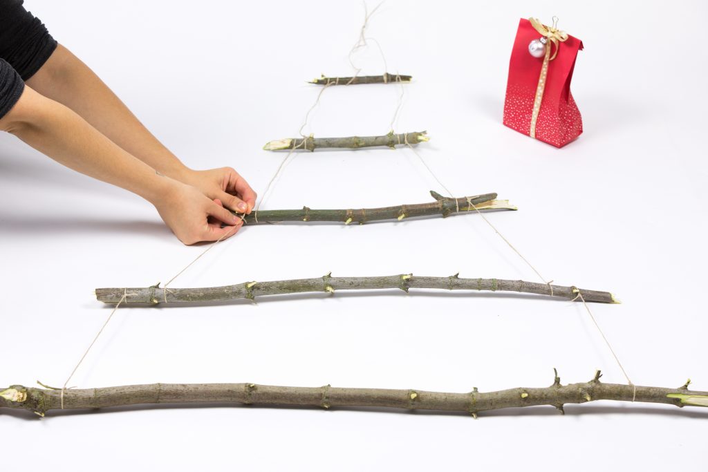 Die Äste sortiert ihr der Größe nach und bindet sie anschließend an den äußeren Enden aneinander fest. So entsteht die Form des Tannenbaums.