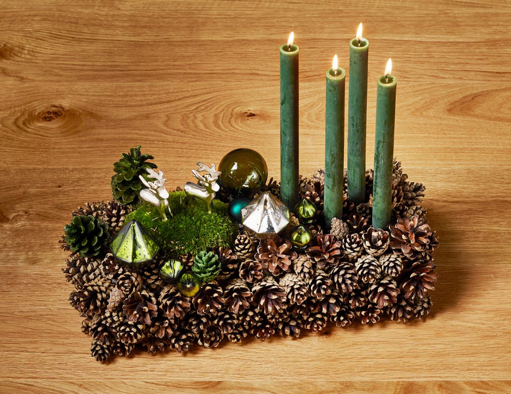 Kleine Weihnachtskugeln und Ornamente bilden funkelnde Highlights zwischen den Naturmaterialien.