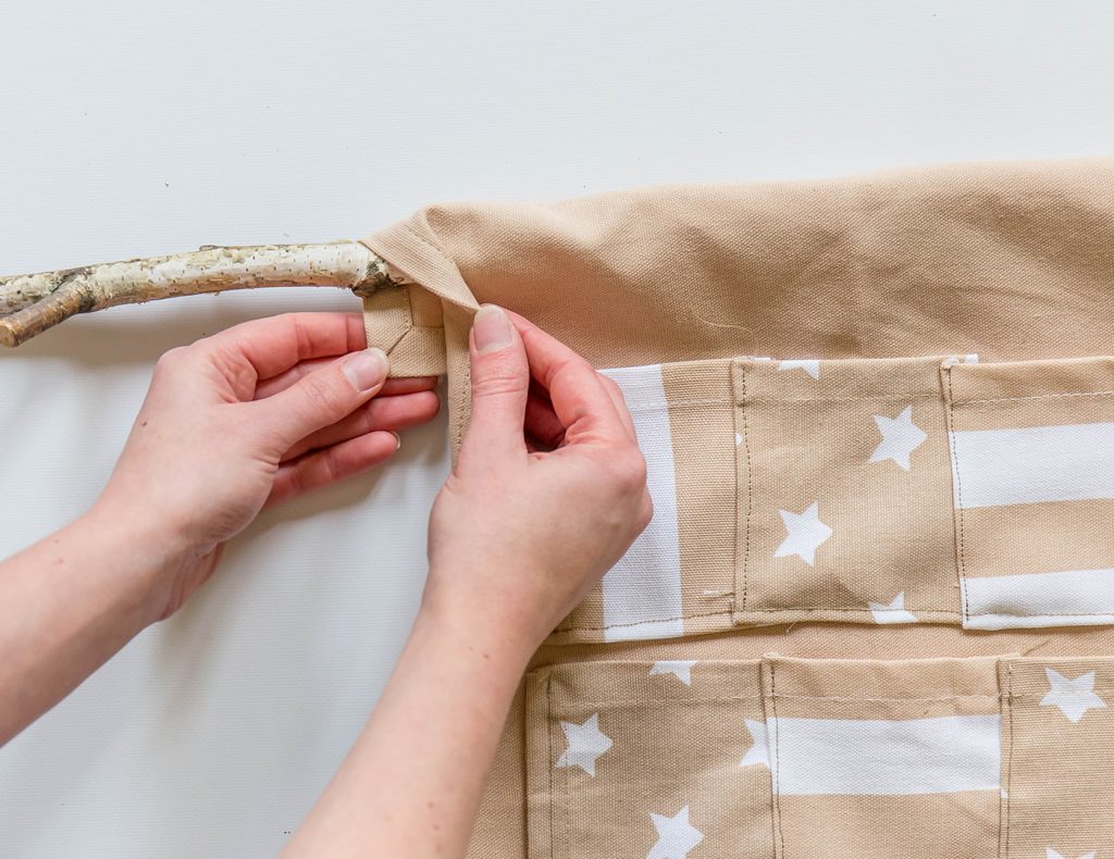 Das obere Ende des Geschirrtuchs wird über den Ast gelegt und festgenäht.