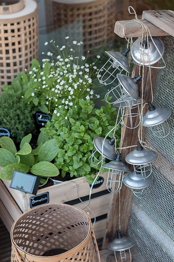 Solarlichterketten lassen den Kräutergarten in Holzkisten auch nach Sonnenuntergang strahlen