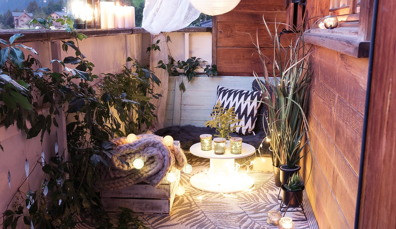 Stimmungsvolle Balkondeko mit Lichterketten und Windlichtern.