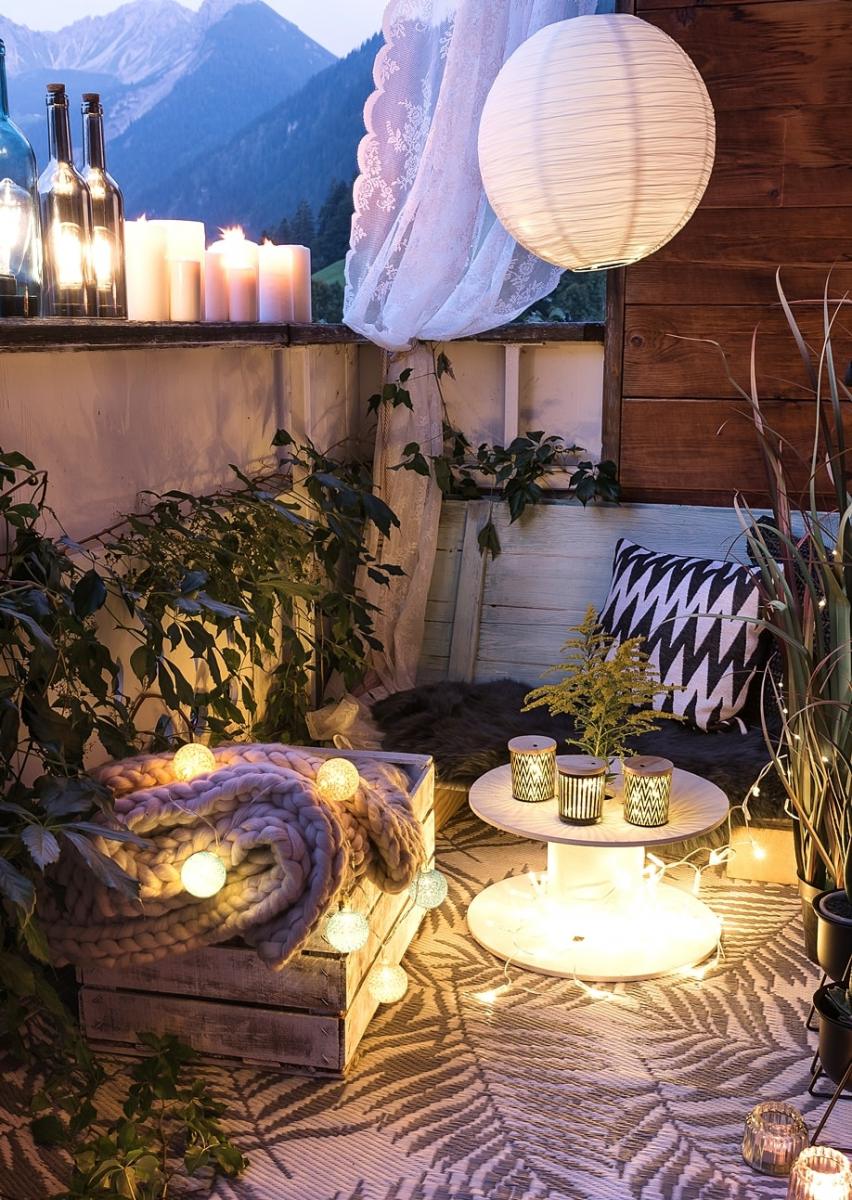 Stimmungsvolle Balkondeko mit Lichterketten und Windlichtern.