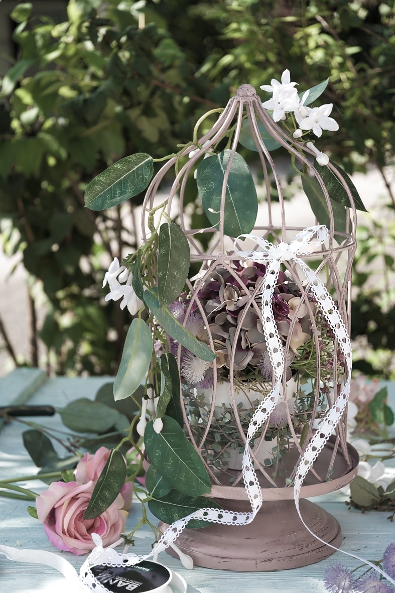 DIY-Geldgeschenk: Dekokäfig geschmückt mit Blumen und gefalteten Geldscheinen