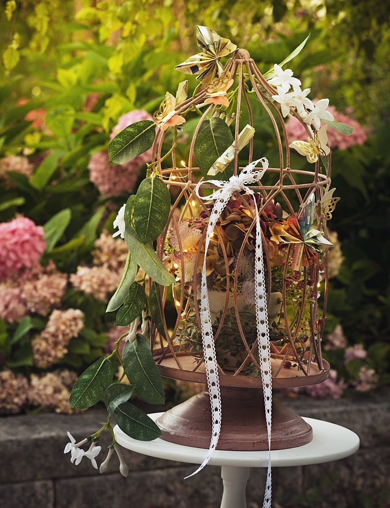 DIY-Geldgeschenk: Dekokäfig geschmückt mit Blumen und gefalteten Geldscheinen