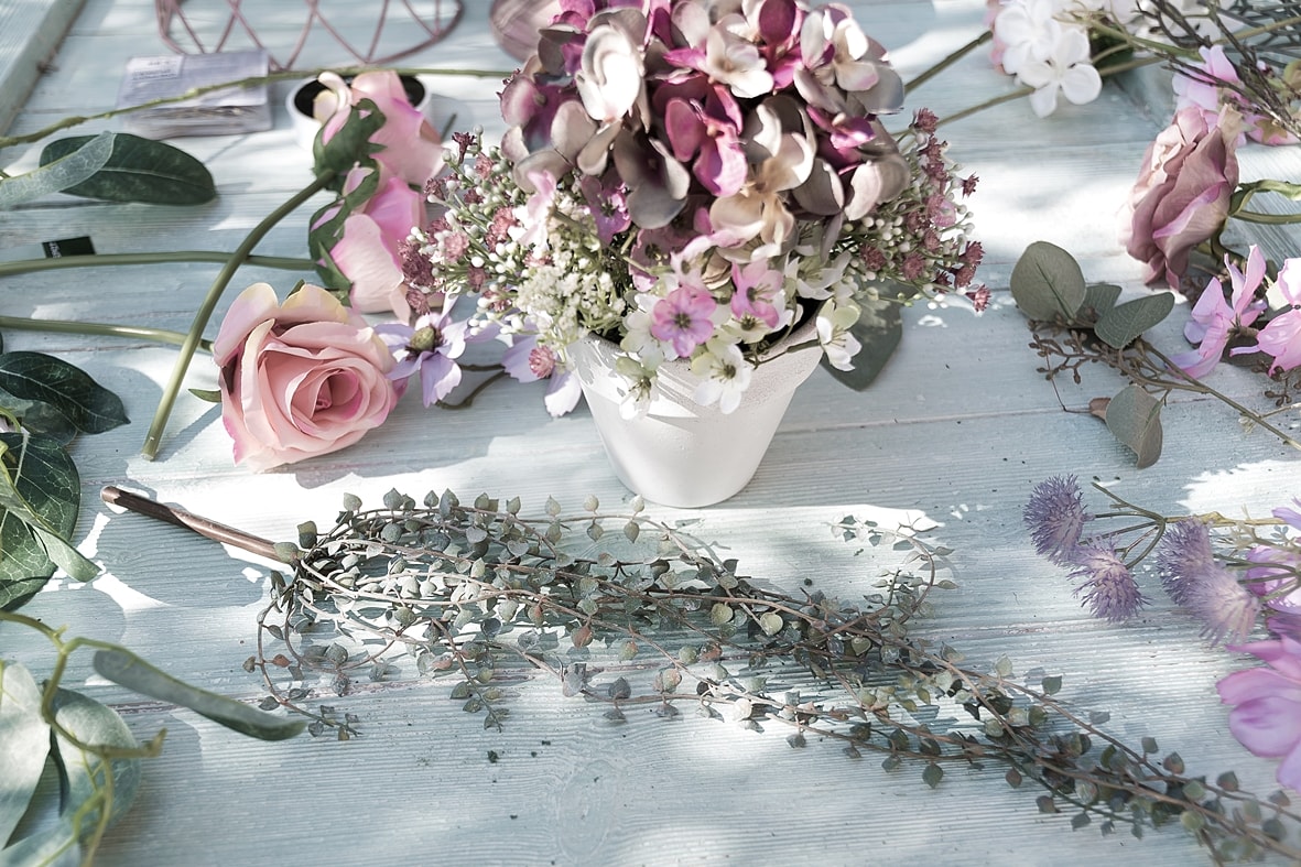 Blumengesteck aus Kunstblumen und Blättergirlande