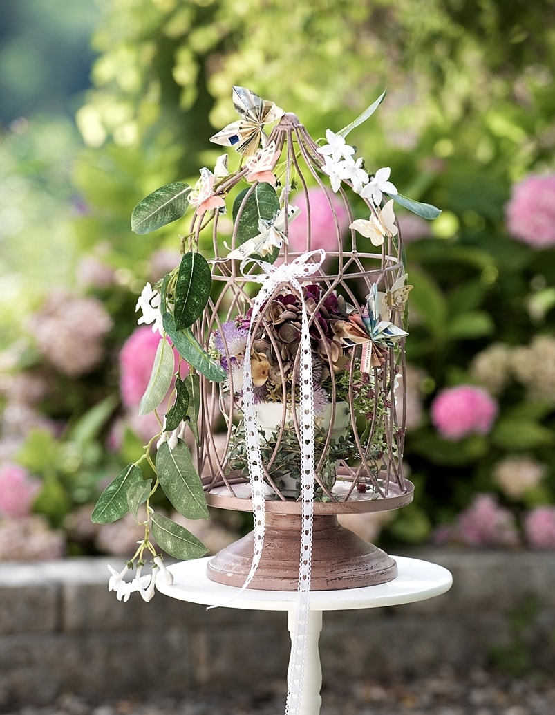 DIY-Geldgeschenk: Dekokäfig geschmückt mit Blumen und gefalteten Geldscheinen