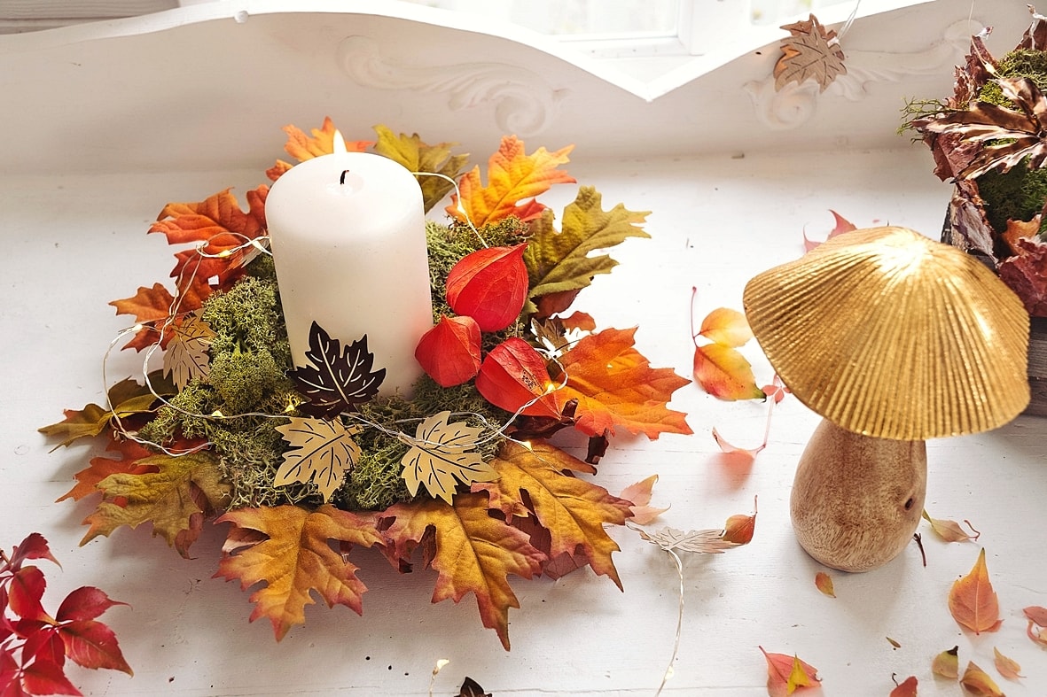 Schale mit Kerze und buntem Herbstlaub.