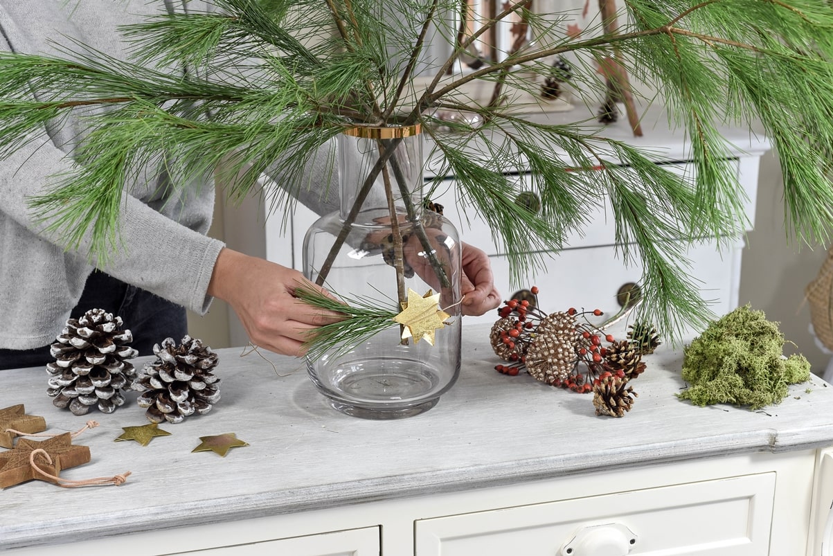 Vase mit Zweig und Stern weihnachtlich schmücken.