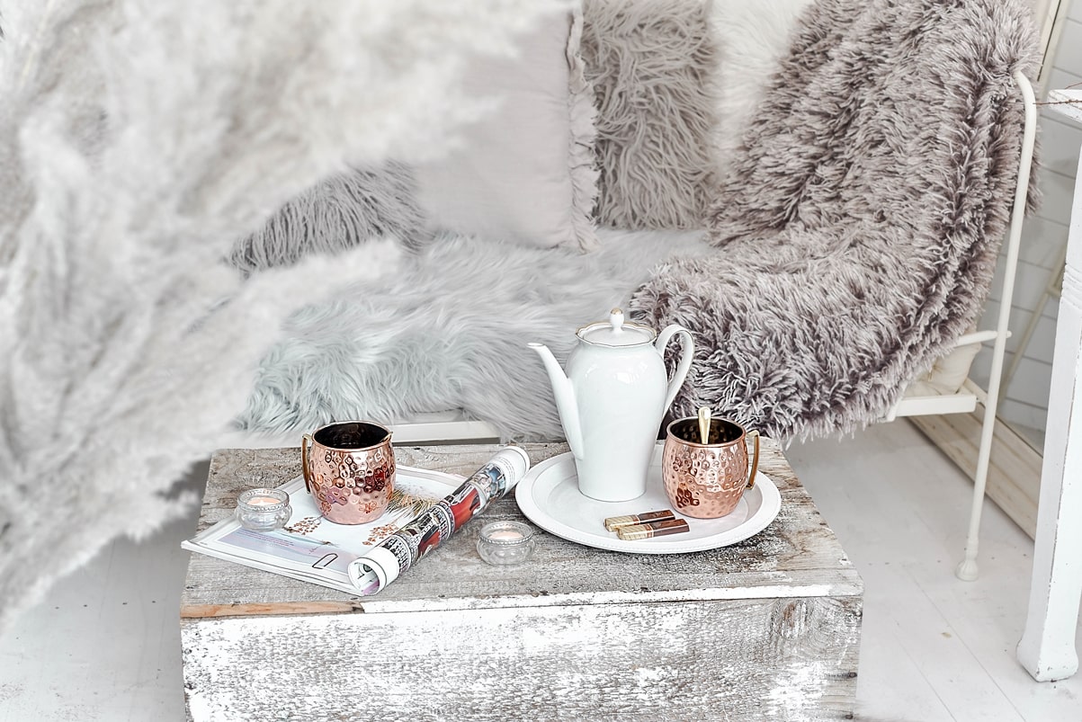 Kuschelige Winterdeko mit Fellen und Kissen.