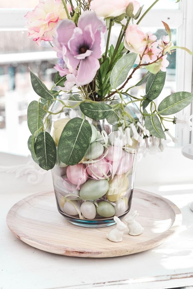 Ostereier und Kunstblumen in der Vase arrangieren