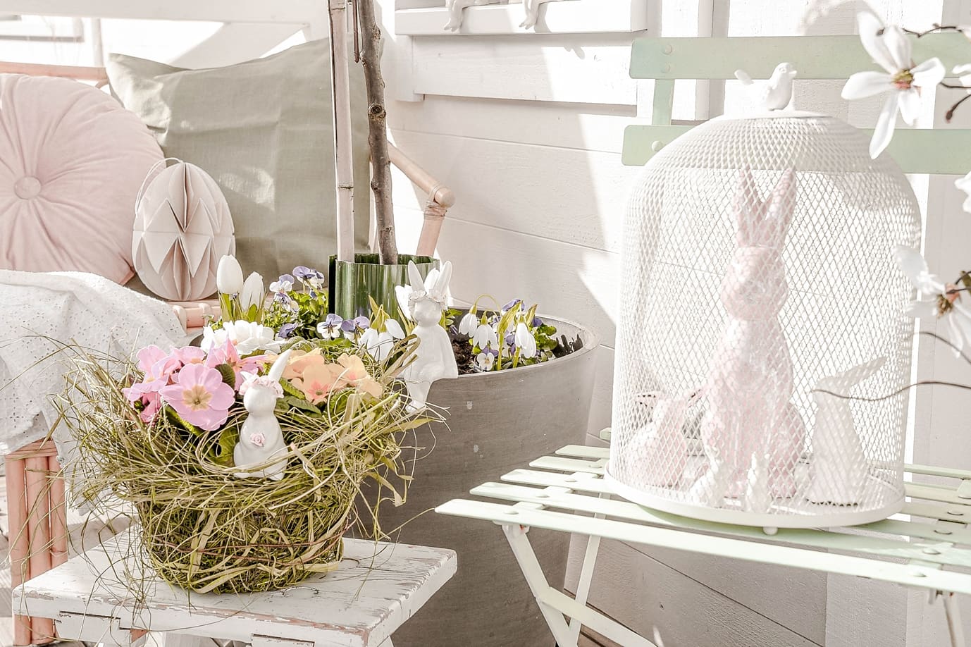 Osterdeko mit Porzellanhasen und Blumen.